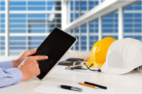 Hand holding tablet on table with hard hats